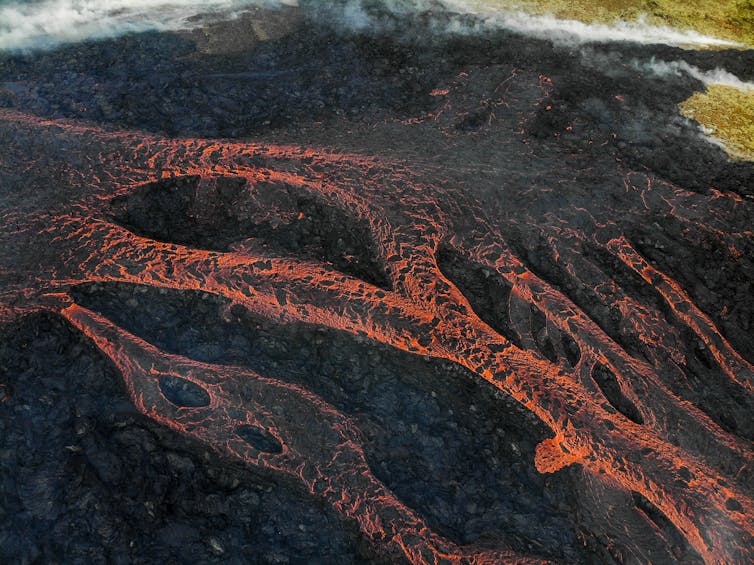 Magma runs downhill in multiple streams over cooled lava.