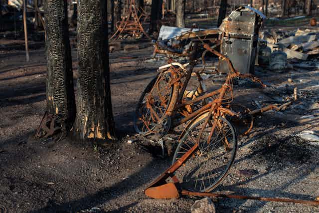 A rusted bicycle in the foreground of a burned out area