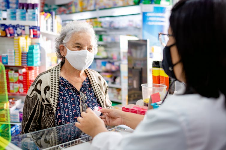 A pharmacist gives an antiviral to an elderly patient.