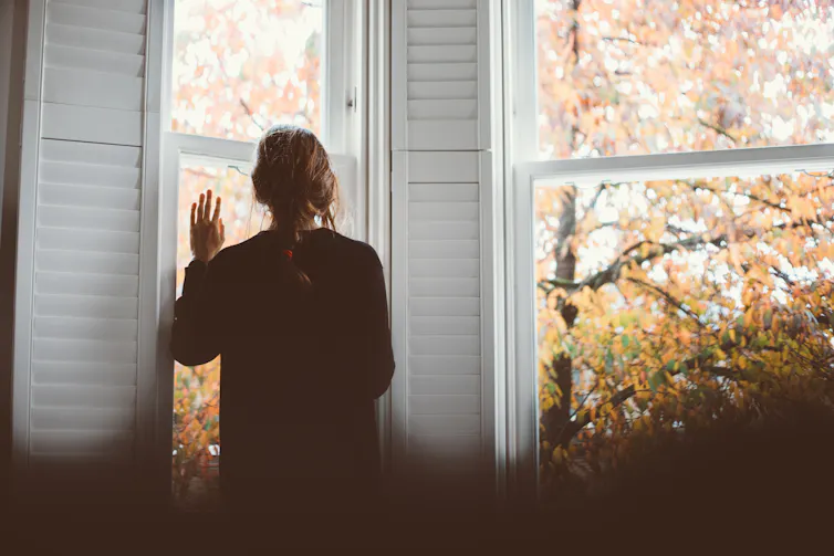 A woman looks out a window.