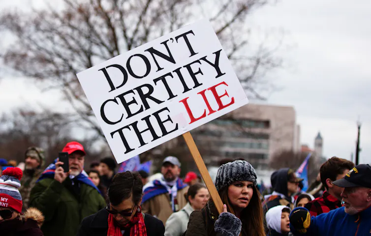 A protester holding a sign that says 'don't certify the lie'