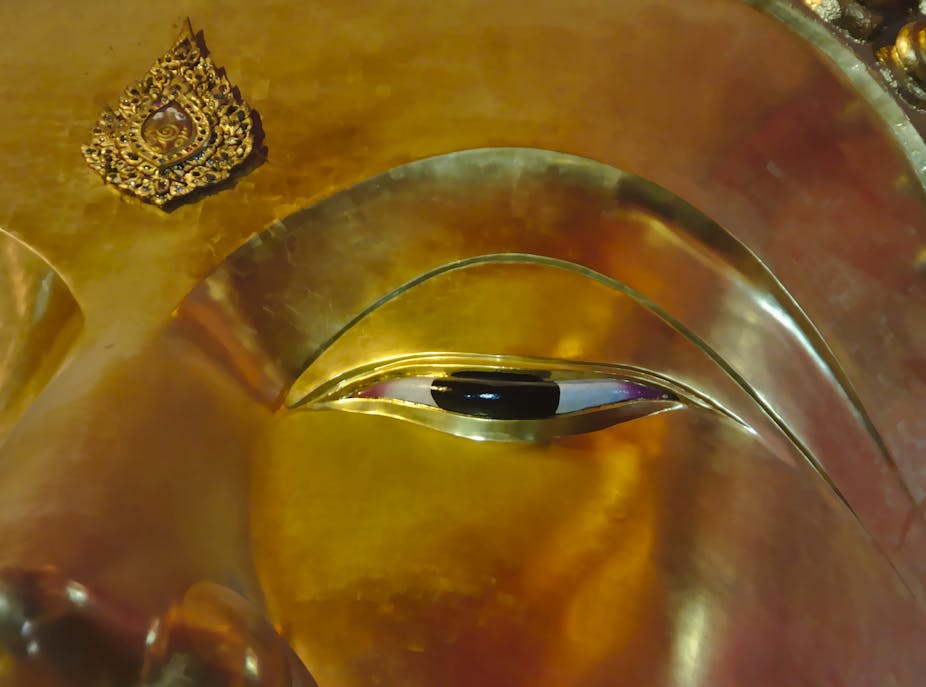 Close-up of a painted open eye of a golden Buddha statue.