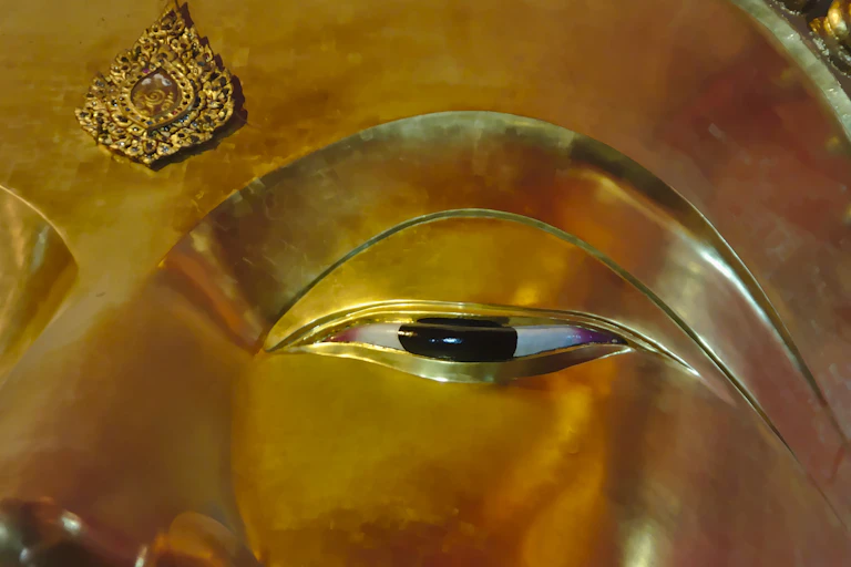 Close-up of a painted open eye of a golden Buddha statue.