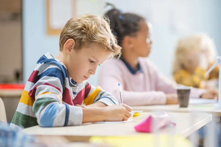 A young boy takes a test in his school classroom.
