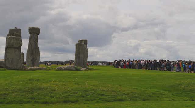A la izquierda, un monumento megalítico. A la derecha, decenas de visitantes haciendo fotos y observando.
