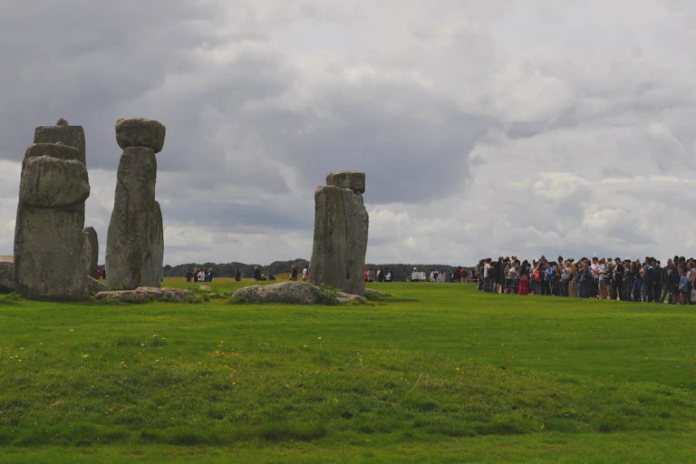 A la izquierda, un monumento megalítico. A la derecha, decenas de visitantes haciendo fotos y observando.