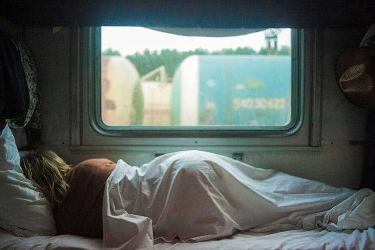 Photo of a woman sleeping in a caravan, from behind.