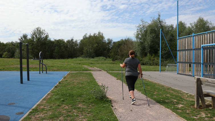 Photo d’une femme pratiquant la marche nordique, vue de dos.