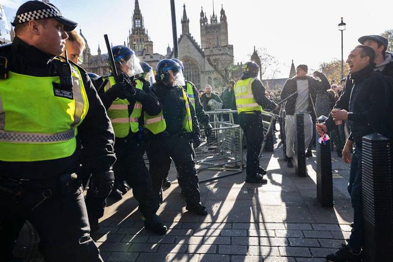 Policemen in bullet-proof vests face off with angry men.
