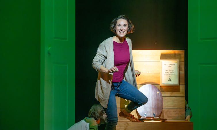 A woman stands in front of a toilet.