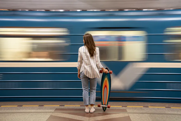 A woman stands in front of a passing train