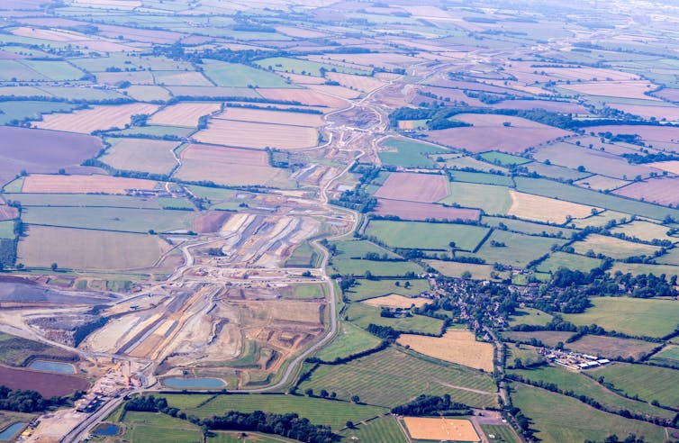 Aerial view of train line construction amid fields.