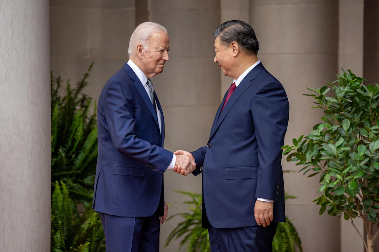 Two men wearing blue suits shake hands, Joe Biden and Xi Jinping.