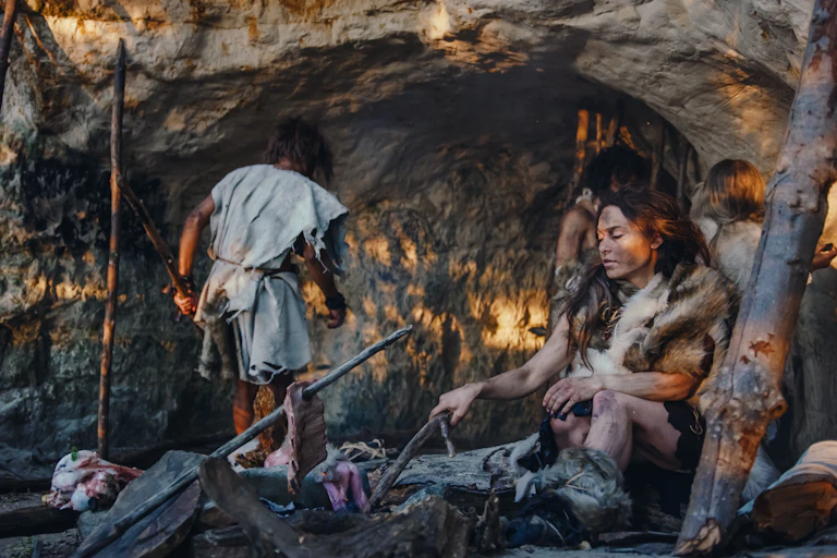 pessoas vestidas com peles do lado de fora de uma caverna, uma mulher sentada em uma fogueira