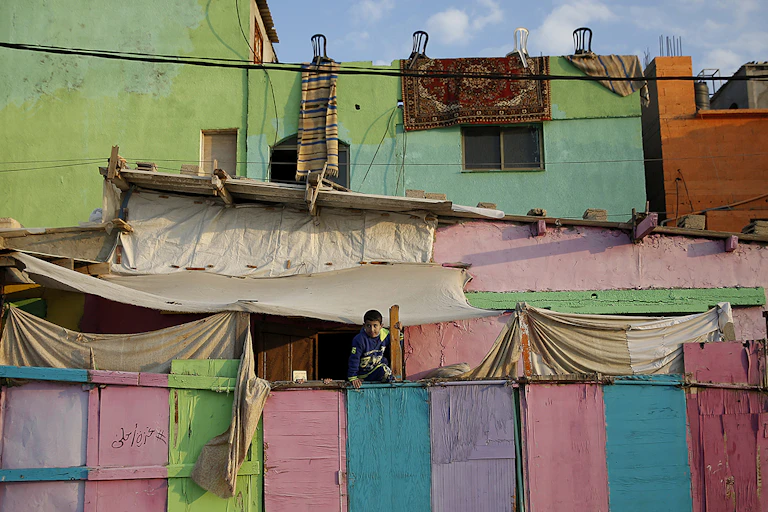 Pink, blue, green and yellow painted panels form a wall, with a boy perched along the top of it.