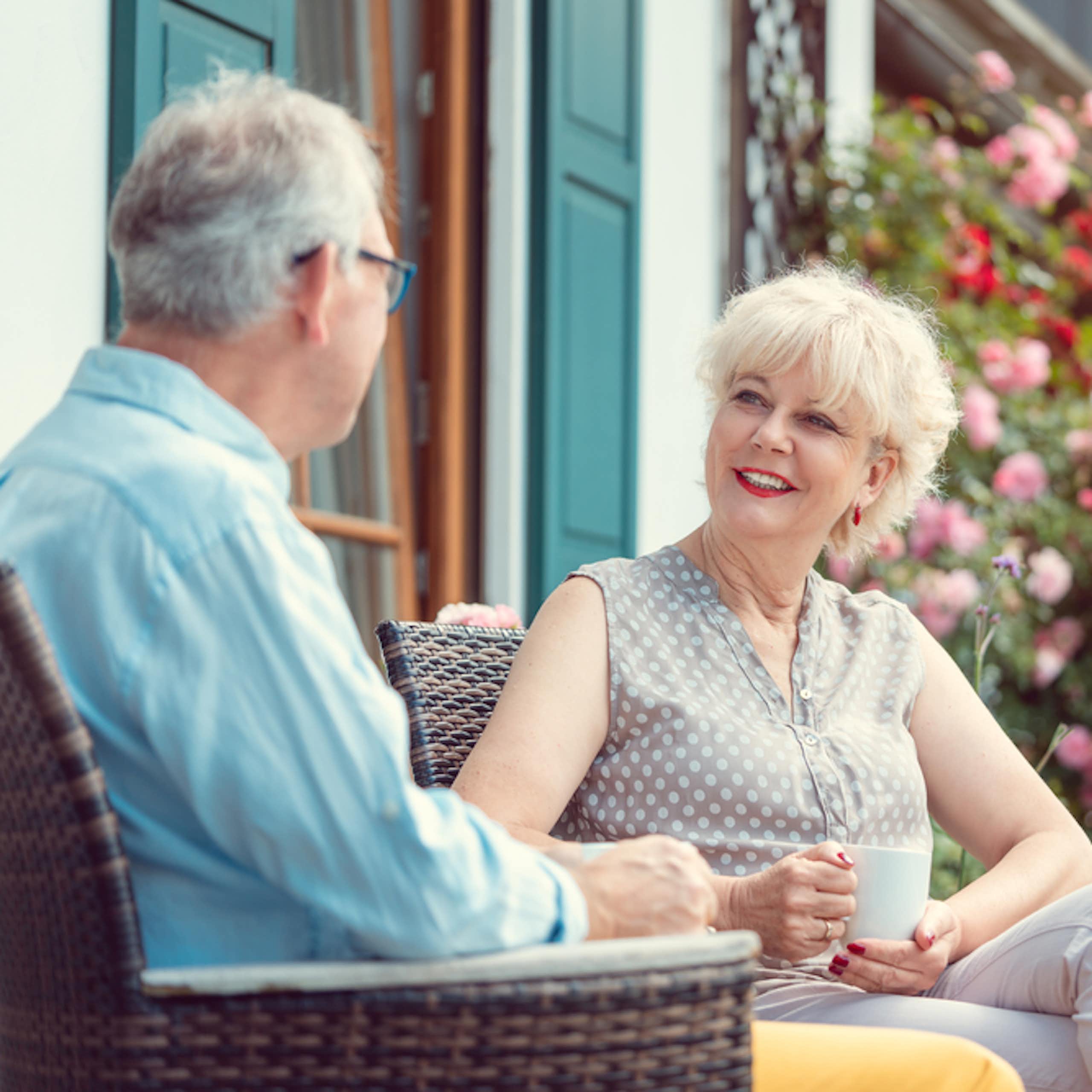 Un couple âgé savourant son café assis sur la véranda devant leur maison