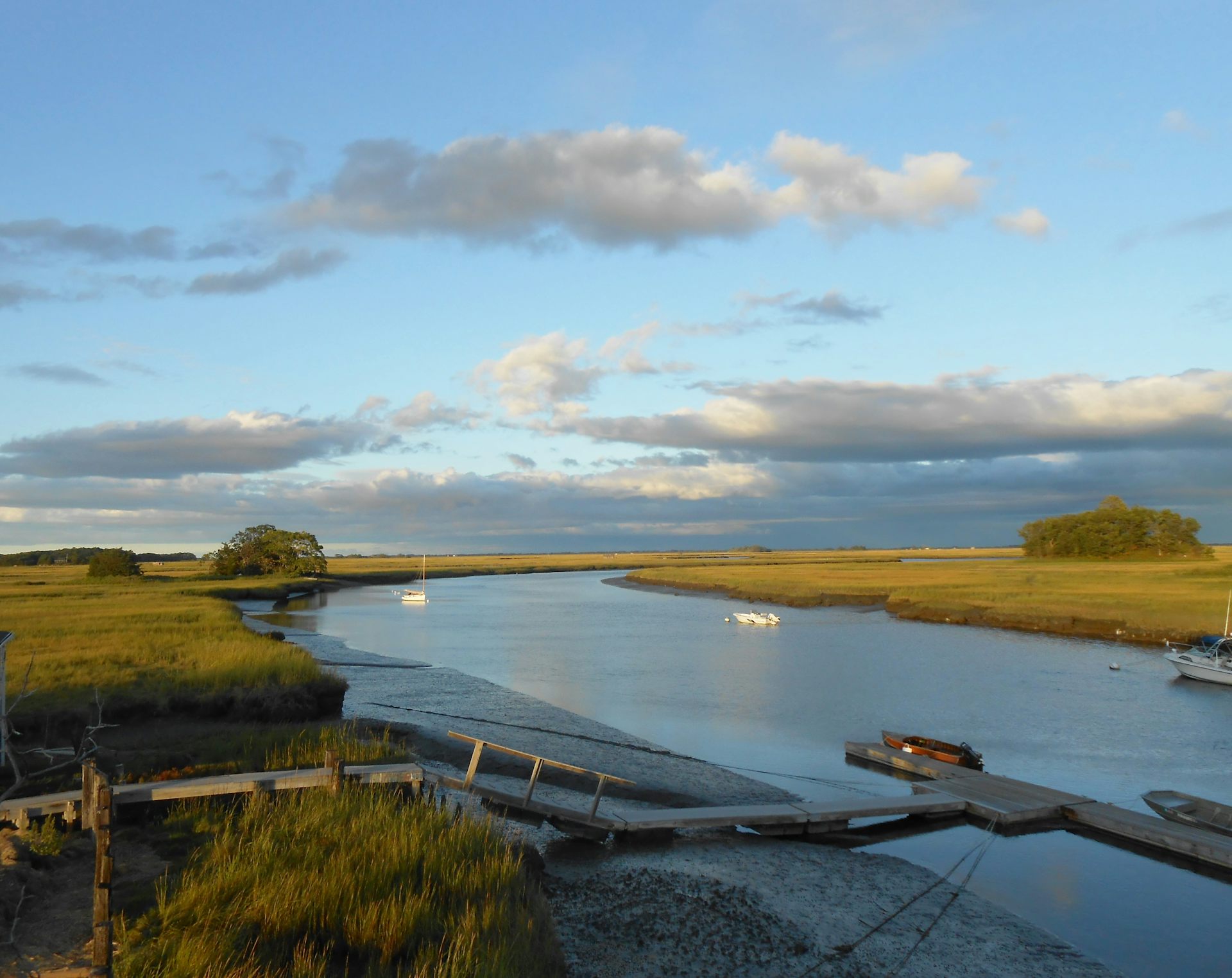 A canal through a marsh, with boats on it.