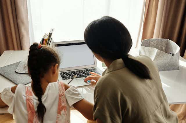A mother and child work at a desk.