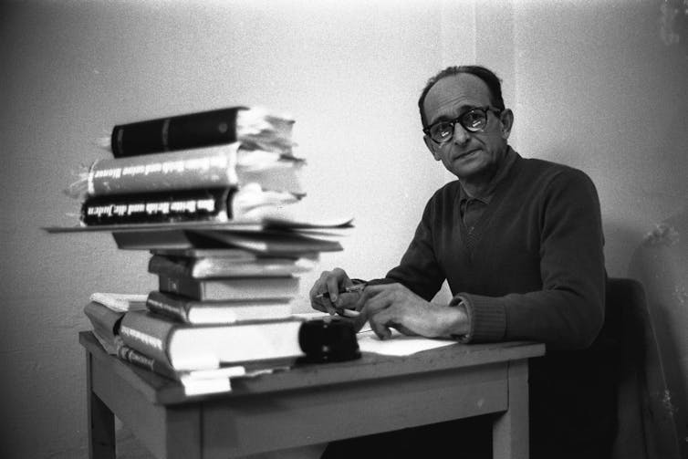 Adolf Eichmann sits with a pile of books in his prison cell.
