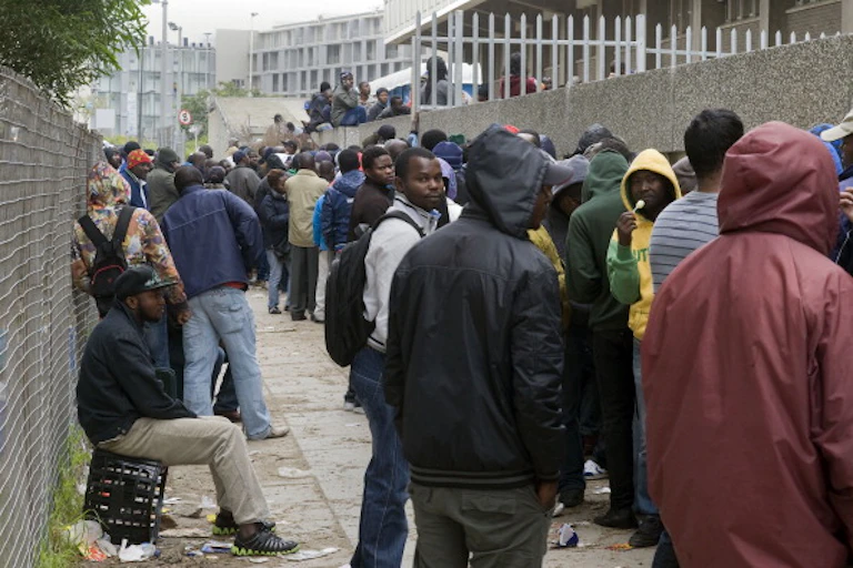 A queue of people standing outside a building.