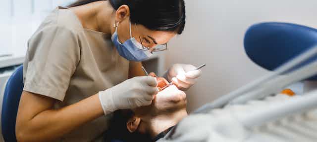Dentist examines person's mouth