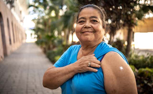 Woman shows arm where she has been vaccinated