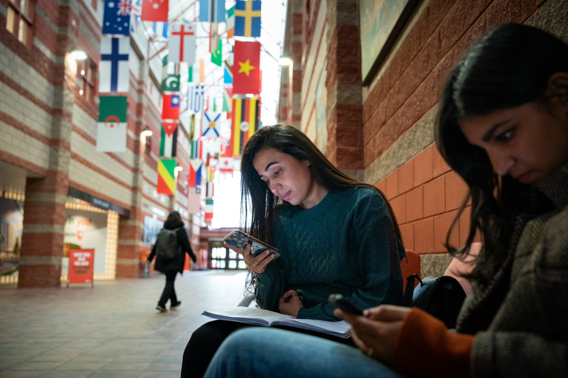 A student seen in a hallway looking at something in their hand.