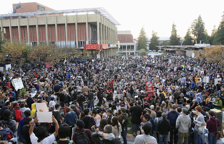 A crowd of people with placards seen outside.