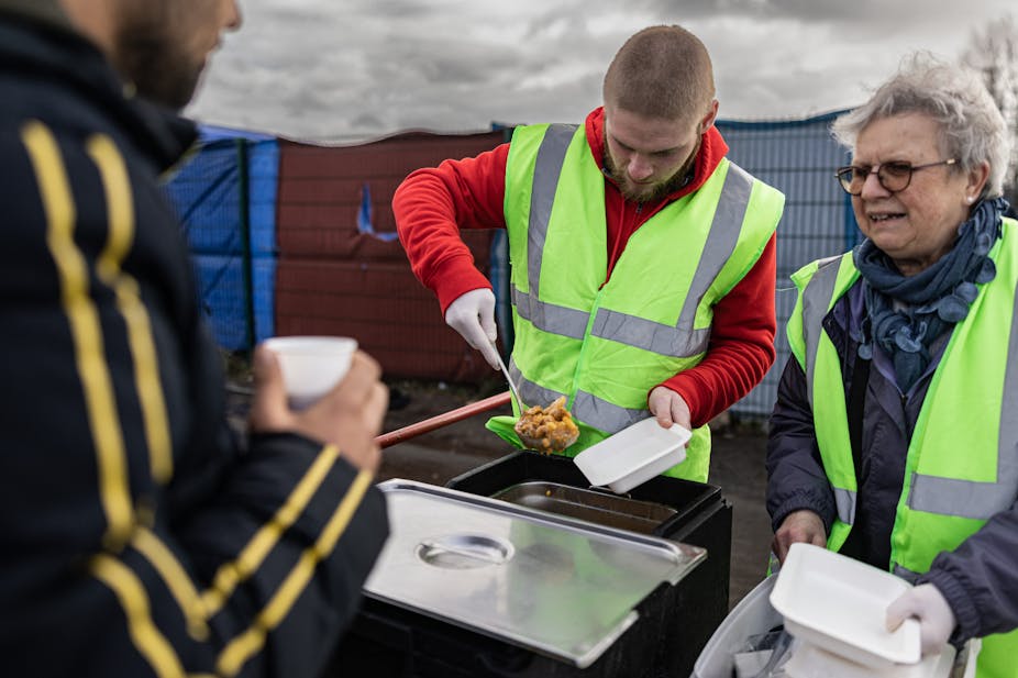 Des bénévoles distribuent des repas aux migrants dans un camp de fortune à Mardyck, dans le nord de la France, le 9 mars 2023.