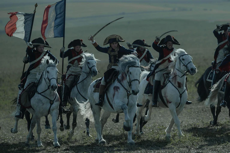 Escena de una película en la que un hombre a caballo con espada lidera a otros que le siguen y portan bandera francesa