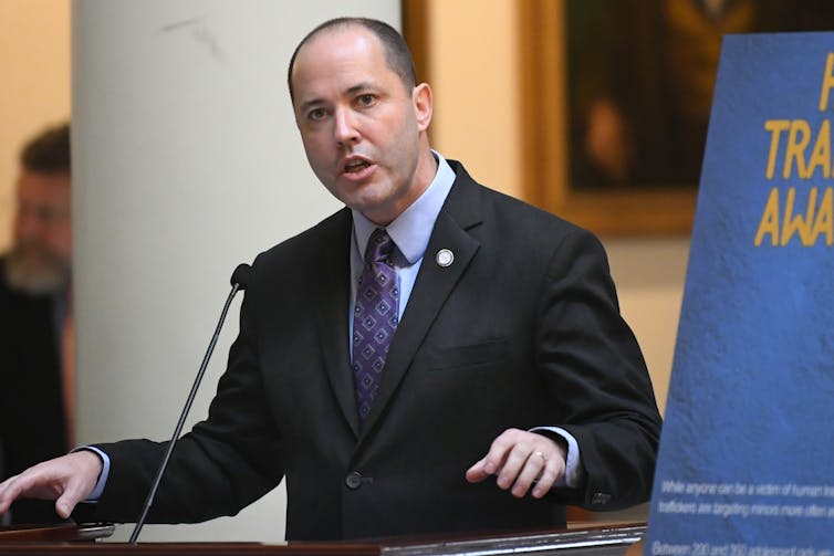 A man in a business suit speaking at a microphone