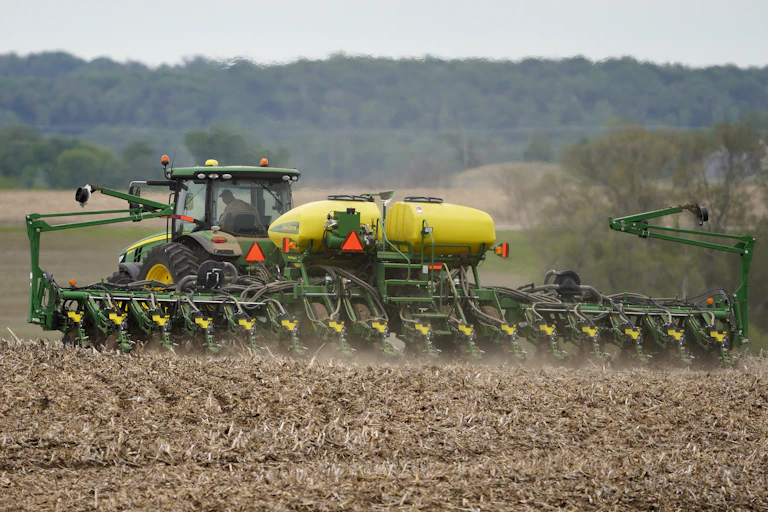 a tractor tows a large piece of machinery across a field