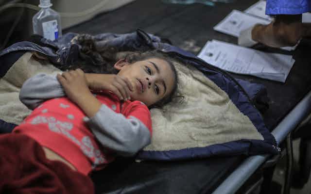 A girl lies on a coat holding her arm.