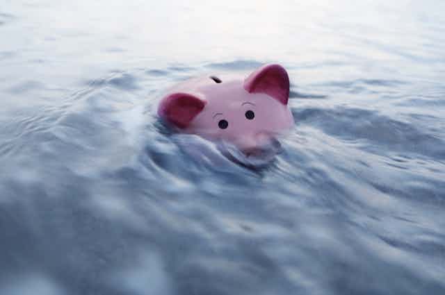 A piggy bank is half submerged in water.