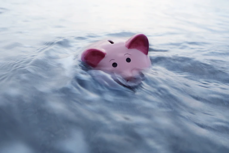 A piggy bank is half submerged in water.
