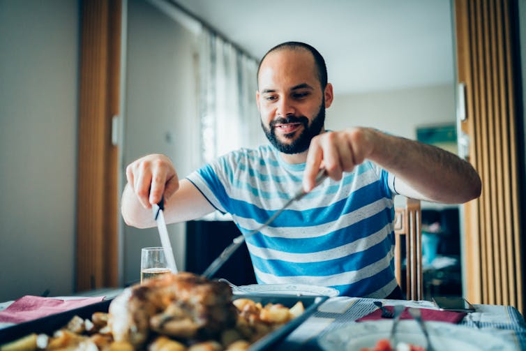 Man carves roast chicken