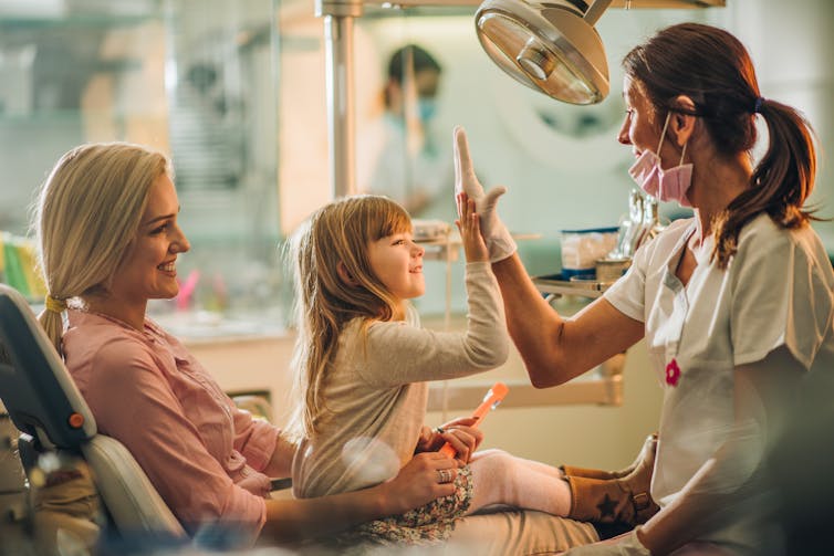 Dentist high-fives child on her mum's lap