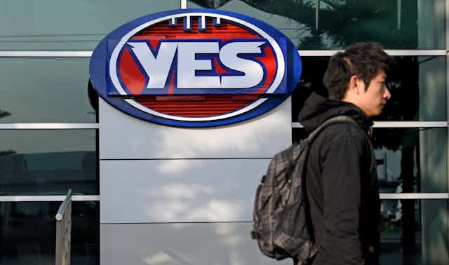 Man wearing a backpack walks past a Yes sign