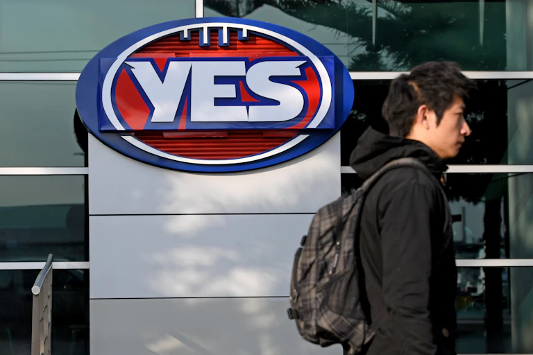 Man wearing a backpack walks past a Yes sign