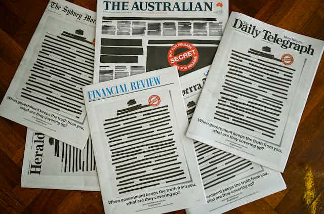 A pile of newspapers with the front pages redacted
