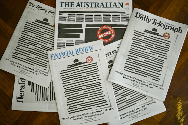 A pile of newspapers with the front pages redacted