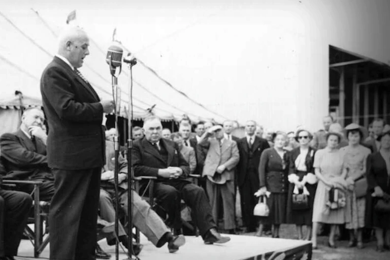 Black and white photo, a man stands on a dias.