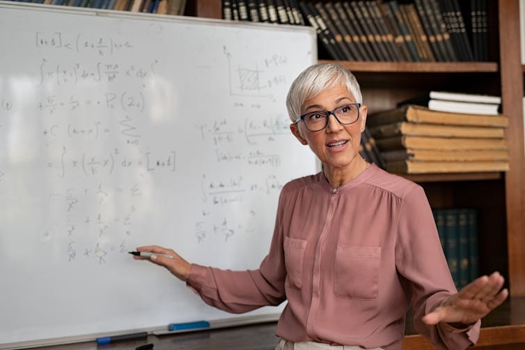 Portrait of senior female professor explaining math formulas.