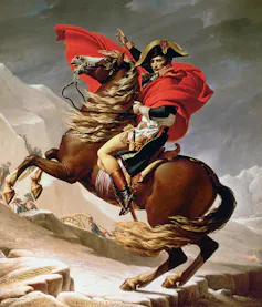 Napoleón con capa roja montado en un caballo.