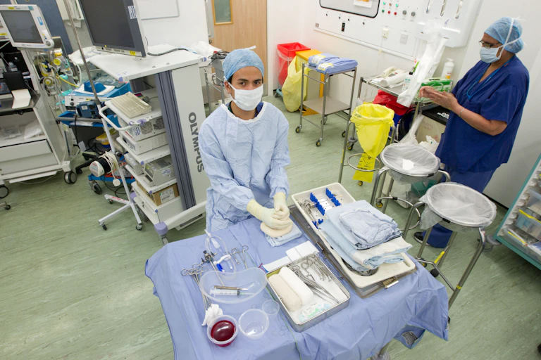 Two people in blue scrubs in an operating theatre.