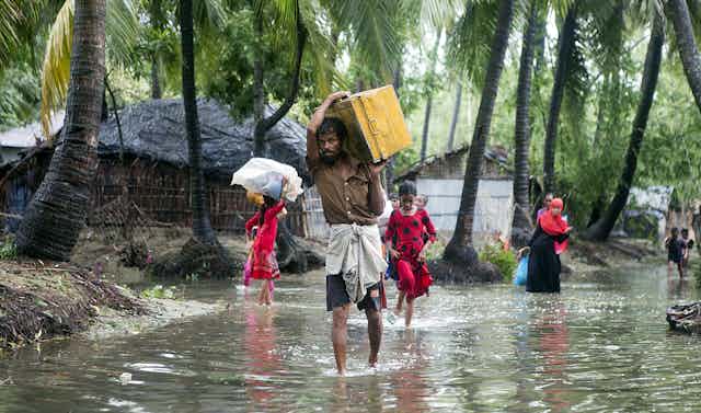 Family walking through flooded village in Bangladesh