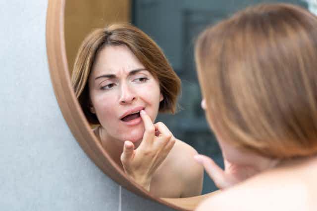 Woman checking her mouth in the mirror