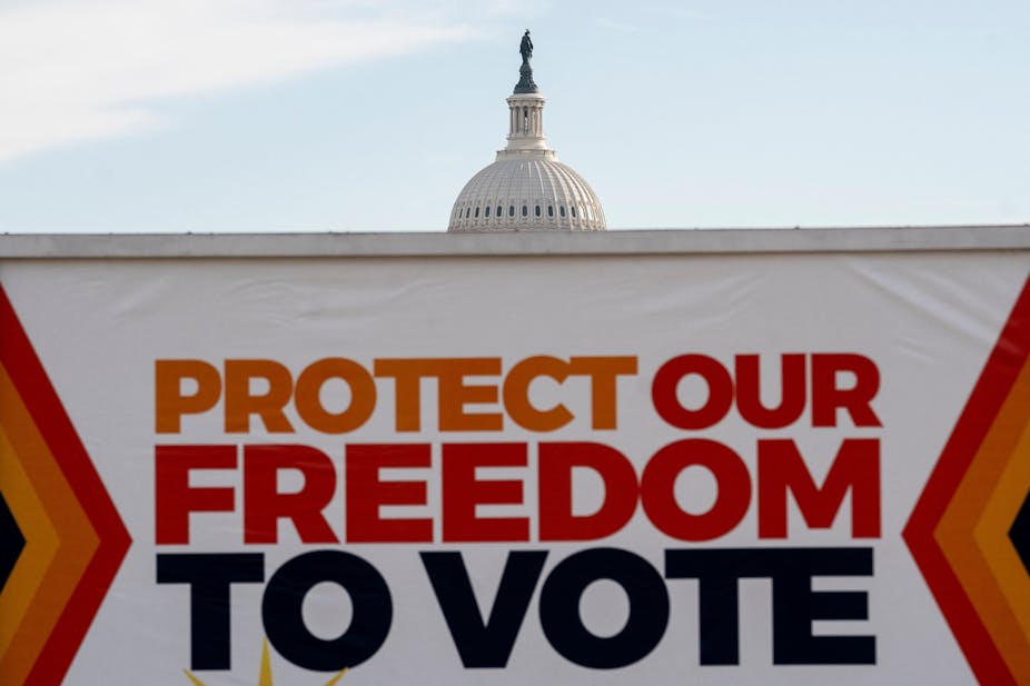 A banner that says 'Protect our freedom to vote' is shown in front of the US Capitol building, obscuring most of it.