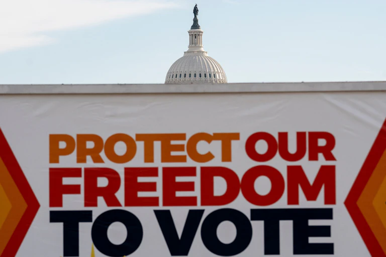 A banner that says 'Protect our freedom to vote' is shown in front of the US Capitol building, obscuring most of it.