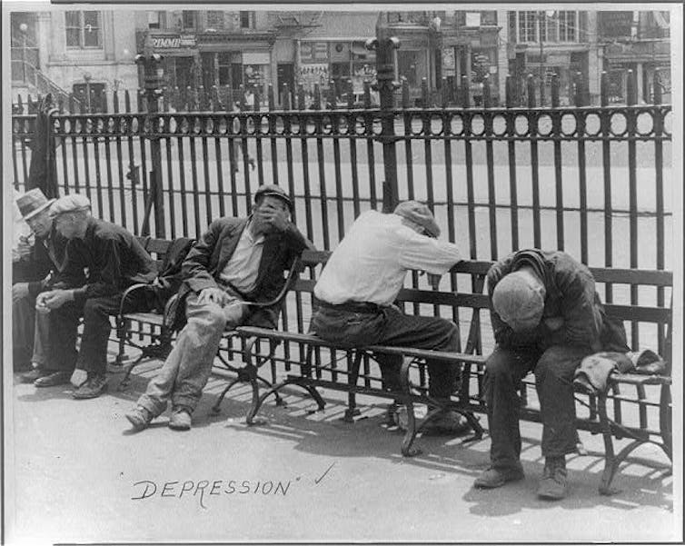 Row of depressed men slumped on benches in front of a city street